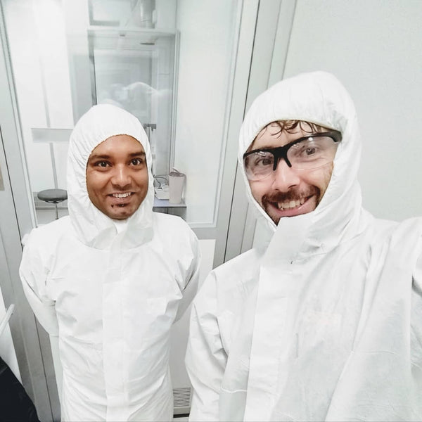 Two men in white protective coverall suits visiting a factory where sun-a-wear UV tracker is produced