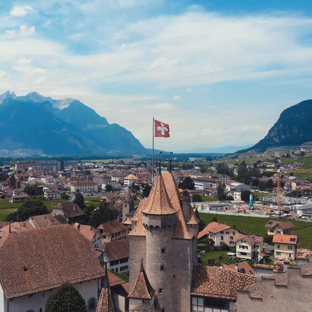 Idilic Swiss town with view of the lake and mountains, focused Swiss flag on top of the old town building